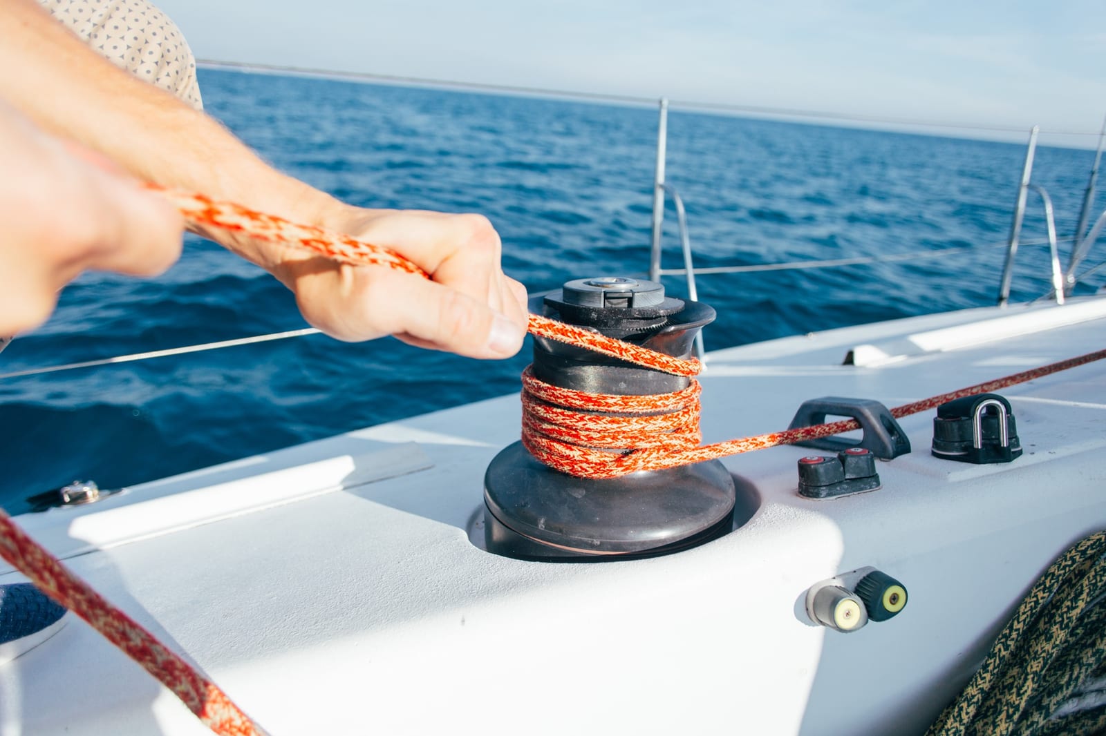 Marinaio professionista che regola la scotta con un verricello su uno yacht a vela